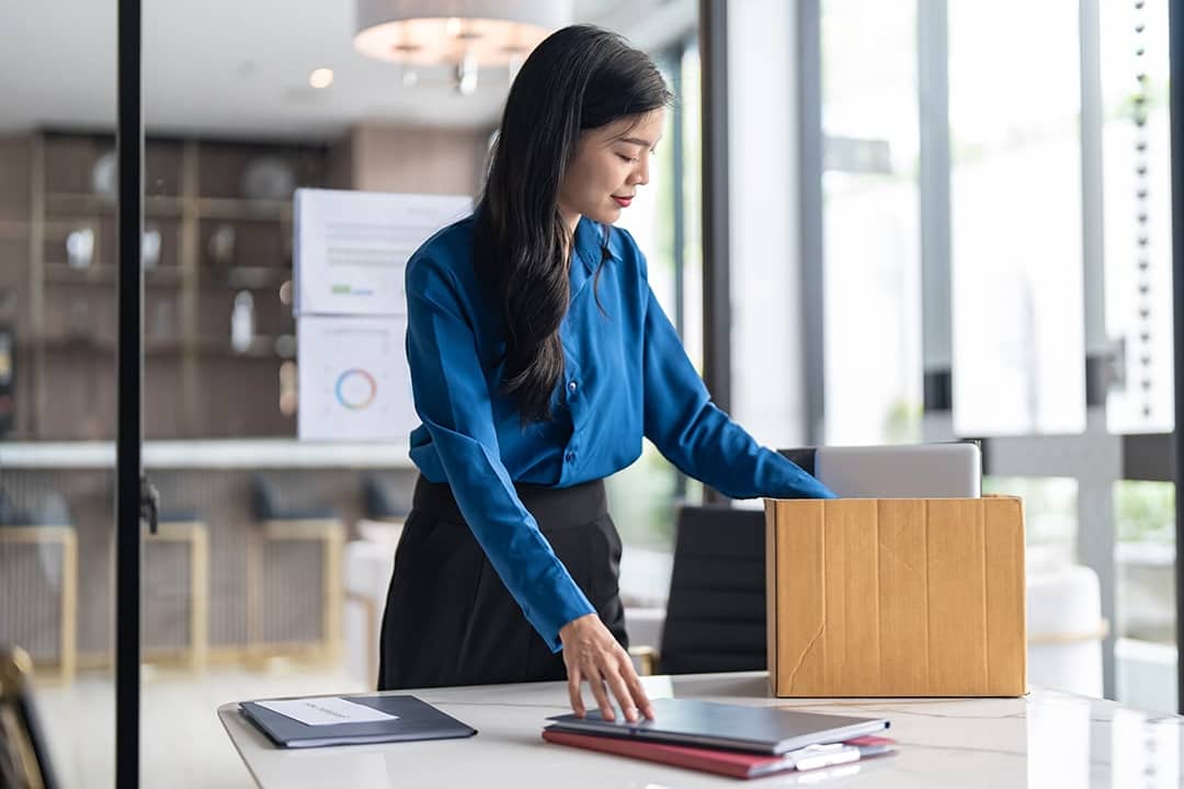 A female employee putting work items in a box for her last day at work.